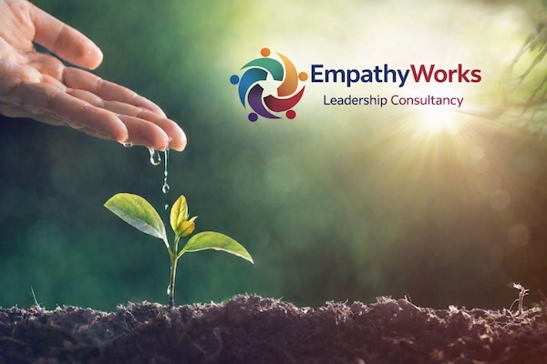A hand nurturing a young plant beneath the EmpathyWorks logo